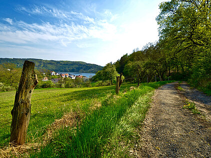 Man sieht Feldweg und Wiese am Mühlenberg mit Blick auf Herzhausen.