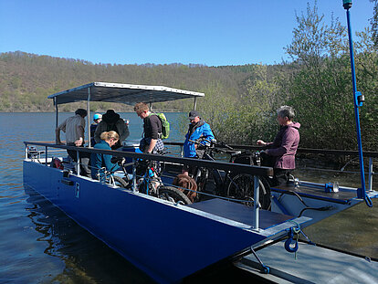 Eine blaue Faehre, die Wanderer und Radfahrer ans andere Ufer des Edersees bringt.